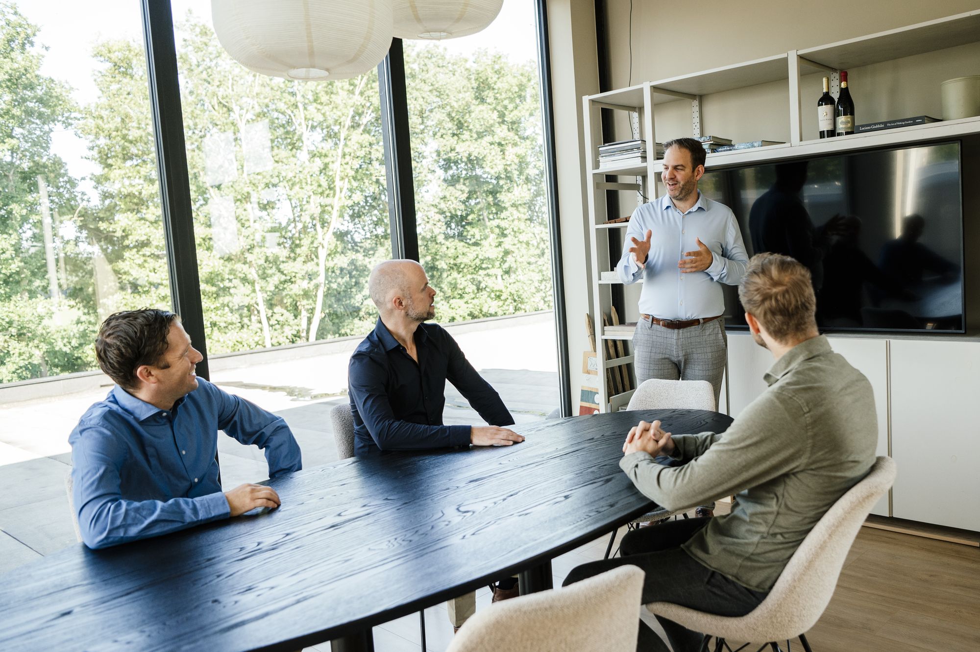 Overleg aan een lange tafel voor een raam met uitzicht op het groen
